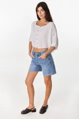 Camisa de lino azul marino, de corte crop y holgado, con cuello redondo, botonadura frontal y mangas amplias con vuelta.