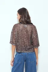 Remera de estilo deportivo con cuello en V y mangas cortas amplias. Presenta un diseño de rayas verticales en tonos marrones, blancos y líneas finas en fucsia, confeccionada en tejido de red.