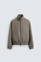 Cazadora de corte relajado confeccionada en tejido con lana, con diseño de pata de gallo en tonos marrones. Presenta cuello subido con cierre de botones, bolsillos laterales de vivo y acabados elásticos en puños y bajo.