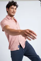 Camisa de manga corta con diseño a rayas verticales en color azul marino y blanco. Presenta cuello clásico, cartera abotonada frontal y logo bordado en el pecho. Posee un corte slim fit.