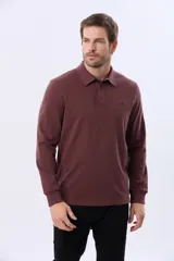 Remera polo de manga larga confeccionada en tejido jersey, con cuello clásico y cierre frontal de tres botones. Presenta un diseño liso con un pequeño logo bordado en el pecho y una etiqueta decorativa en el ruedo.