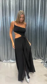 Vestido largo negro con brillos, escote asimétrico de un solo hombro, cut-out en la cintura y detalle de lazo en el lateral.