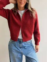 Cardigan tejido de textura suave con cierre frontal de doble vía, cuello alto y mangas largas. Presenta terminaciones en rib en puños y cintura, con un diseño versátil y moderno.