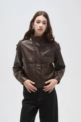 Campera de eco-cuero negro con cuello alto, cierre frontal, bolsillos con solapa en el pecho y puños y ruedo elásticos.