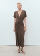 Vestido midi de color marrón, con escote en pico, manga corta y detalle de fruncido central en la cintura que crea un efecto drapeado.