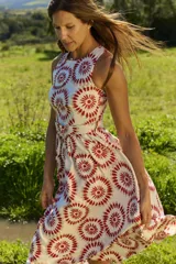 Vestido midi sin mangas, con cuello redondo y diseño estampado en tonos rojos y beige sobre base blanca. Incluye un cinturón ajustable de la misma tela en la cintura y falda con vuelo.