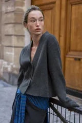 Chaqueta de punto gris oscuro con escote en pico, manga larga y cierre frontal con tres botones.