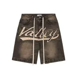 Short de jean estilo baggy con efecto lavado desgastado en color negro. Presenta un aplique frontal grande con la palabra 'Valley' bordada y decorada con cristales de colores, además de cordones largos en la cintura.
