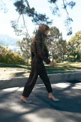 Pantalón de tiro medio con corte barrel, caracterizado por su silueta holgada en cadera y muslos que se estrecha hacia el tobillo. Presenta estampado animal print, bolsillos delanteros y cierre frontal con cremallera, botón y gancho.