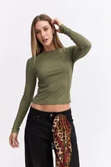 Remera de manga larga color beige, con ajuste al cuerpo y costuras decorativas visibles en el frente que realzan la silueta.