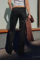 Jeans de tiro bajo con corte recto, confeccionados en denim negro con efecto lavado. Presentan cinco bolsillos, trabillas para cinturón y cierre frontal con cremallera y botón metálico.