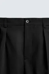 Pantalón de corte wide fit confeccionado en algodón, con pliegues frontales dobles, bolsillos laterales y bolsillos traseros de doble vivo. Presenta cierre frontal con cremallera y botón.