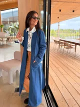 Tapado largo de jean azul, con diseño abierto sin botones, mangas largas y tajos laterales profundos. Confeccionado en denim suave y flexible.