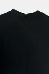 Vestido largo negro de cuello redondo y manga corta, con detalle de drapeado lateral, bajo con abertura lateral y cierre de cremallera en la espalda.