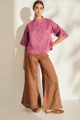 Camisa de lino color fucsia, con cuello mao, mangas cortas holgadas y cierre frontal con botones de madera. Cuenta con bolsillos frontales en el pecho.