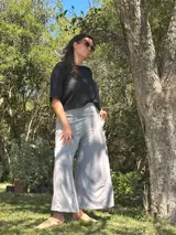 Conjunto compuesto por una blusa negra de corte holgado y mangas cortas, y un pantalón palazzo gris de tiro alto con faja ancha en la cintura y bolsillos laterales.