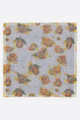Chal cuadrado con estampado floral sobre un fondo de cuadros azules y blancos. Tiene bordes desflecados.