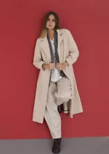 Tapado largo de corte clásico confeccionado en tela de paño fantasía tipo boucle, con cuello de solapa amplio, bolsillos laterales y cierre frontal con botones. Presenta cortes verticales para un mejor entalle y un tajo en la parte posterior.