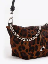 Bandolera de tamaño pequeño confeccionada en pelo vacuno con estampado animal print de leopardo y detalles en cuero vacuno flor. Presenta una cadena metálica decorativa en el frente, aplique metálico con logo JCH y correa de cuero ajustable.