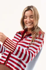 Saco tejido de punto a rayas horizontales en color celeste y rojo, con cuello alto, cierre frontal doble deslizador y puños con diseño en contraste. Presenta un pequeño bordado en el pecho.