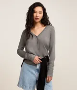 Cardigan de punto color gris, con escote en V, cierre frontal con botones y manga larga.