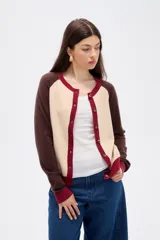 Cardigan de punto con diseño color block, presenta cuerpo en color celeste, mangas en color bordó y detalles de botones y bordes en color rosado. Posee cuello redondo y mangas largas.
