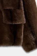 Abrigo corto de Zara con diseño de efecto pelo, cuello de solapa con muescas, manga larga y bolsillos frontales con solapa. Cuenta con forro interior a tono y cierre frontal con botón.