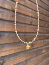Collar de cristales facetados en tonos rosados, blancos y dorados, con un dije colgante en forma de flor con circonia en el centro.