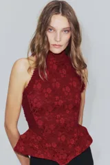 Corset bordó de cuello halter con hombros descubiertos, confeccionado con combinación de tejidos con patrón floral, detalles de volados en las sisas y bajo en peplum. Cuenta con cierre en la espalda con cremallera.