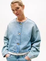 Campera de denim rígido en mezcla de algodón y lyocell, color celeste lavado. Presenta un corte cropped y oversize, sin cuello, con cierre frontal de tres botones dorados cepillados y hombros caídos.