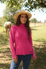Polera de tejido de punto acanalado en color fucsia, con cuello alto y mangas largas con puños ajustados. Presenta un pequeño bordado en el ruedo inferior.