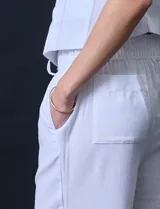 Pantalón de lino de corte recto y tiro medio, con pretina elástica ancha y lazo de ajuste frontal. Presenta bolsillos laterales verticales y bolsillos traseros.