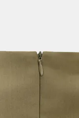 Top sin mangas color verde oliva, con cuello alto y cierre frontal de botones metálicos decorativos. Presenta un corte ajustado en el torso que se ensancha ligeramente hacia el bajo, con detalles de trabillas horizontales a la altura de la cadera.