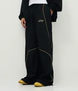 Pantalón deportivo de microfibra color negro, con corte holgado y diseño de piping contrastante en color amarillo. Cuenta con cintura elástica con cordón de ajuste, bolsillos laterales y logo bordado.
