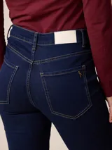 Jean de corte recto y tiro alto, confeccionado en denim azul oscuro con costuras en contraste. Presenta diseño clásico de cinco bolsillos, cierre frontal con botón y bragueta.