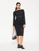 Pollera tubo negra confeccionada en tela de punto calada, con cintura elastizada, calce ajustado y pollera corta interna.