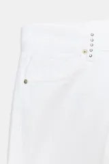 Jeans de tiro bajo y pierna ancha, color blanco, de corte amplio y largo completo. Cuenta con cinco bolsillos, cierre frontal con cremallera y botón metálico, y detalle de tachas decorativas en la zona de la cintura.