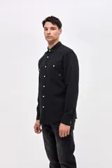 Camisa de corte regular confeccionada en algodón, con cuello clásico, cierre frontal de botones y dos bolsillos frontales en el pecho.