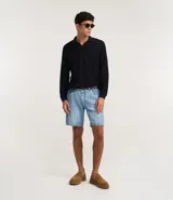 Polo de manga larga color beige claro, confeccionado en tejido texturizado (posiblemente acanalado o waffle). Presenta un cuello polo con escote profundo en V sin botones.