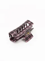 Pinza para el pelo de diseño rectangular con estampado de cuadros escoceses en tonos rosados y negros. Cuenta con un mecanismo de resorte metálico central para una sujeción firme.