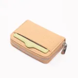 Monedero pequeño color camel con cierre de cremallera y bolsillo externo para tarjetas en color verde claro.