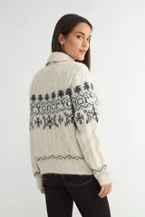 Saco de punto con cuello tipo polo, cierre frontal de botones oscuros y diseño de estampado jacquard en tonos grises y beige. Presenta mangas largas con puños acanalados y textura suave.