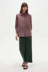 Camisa de algodón a rayas en tonos bordo y blanco, de manga larga, con cuello camisero, cierre frontal de botones y un bolsillo aplicado en el pecho.