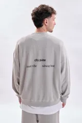 Sudadera gris claro con efecto lavado, de corte holgado y manga larga. Presenta una estampa minimalista en la espalda con el texto 'city pulse', 'street vibe' y 'subway beat'.