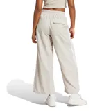 Pantalon Adidas de mujer, de corte ancho y estilo deportivo, color beige con las icónicas tres tiras blancas laterales y logo de la marca bordado.