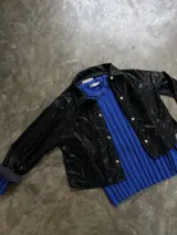 Camisa negra de cuero sintético con botones dorados.