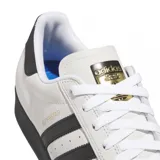 Zapatillas Adidas Superstar ADV color blanco hueso con puntera de goma negra, tres tiras laterales negras y contrafuerte trasero negro.