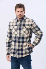 Campera leñadora de viyela a cuadros en tonos beige y azul oscuro, con interior forrado en corderito, cierre frontal con botones y dos bolsillos con solapa en el pecho.