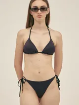 Corpiño de bikini tipo triángulo con tirantes finos que se atan al cuello y a la espalda. Confeccionado en tela swim lurex con textura acanalada, de color azul oscuro o negro con brillo. Incluye almohadillas removibles.