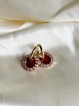 Aros de acero quirúrgico con dije circular de resina rosa y borde de strass dorados.